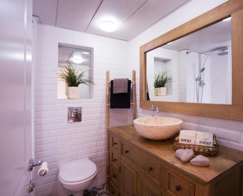 een badkamer met een wastafel, een toilet en een spiegel bij Alma in Caesarea