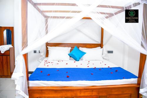 une chambre avec un lit avec des fleurs rouges dessus dans l'établissement Serendib villa unawatuna, à Unawatuna