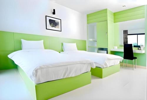 een groene en witte slaapkamer met twee bedden en een bureau bij Siamgrand Hotel in Ban Nong Saeng