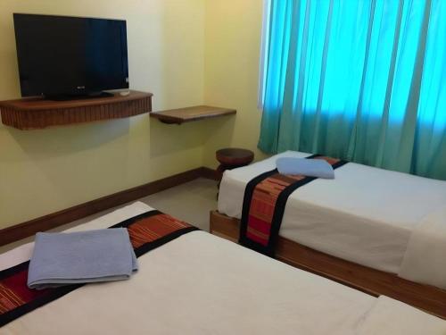 a room with two beds and a flat screen tv at Lankham Hotel in Pakse