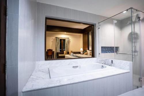 Un baño con bañera y un espejo grande. en Wiangkaew Hotel, en Ban Fai Kaeo
