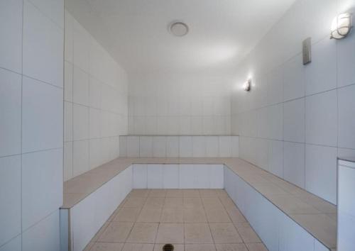 Una habitación blanca con un banco largo en ella. en One-Bedroom Lagoon Spa Apartment, en Salamander Bay