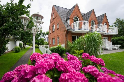 a house with pink flowers in front of it at Hotel Landhaus Ellerbrock in Sankt Peter-Ording
