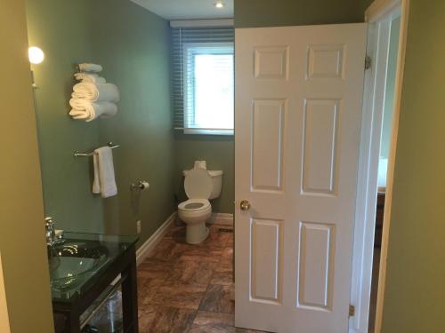 a bathroom with a toilet and a sink and a door at Grey Rose Suites in Hanover