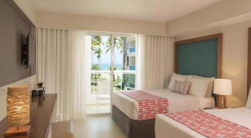 a hotel room with two beds and a balcony at Celuisma Playa Dorada All Inclusive in Sampiño