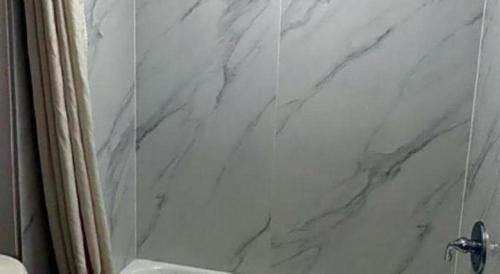 y baño con cortina de ducha de mármol y aseo. en Scottish Inns Augusta, en Augusta