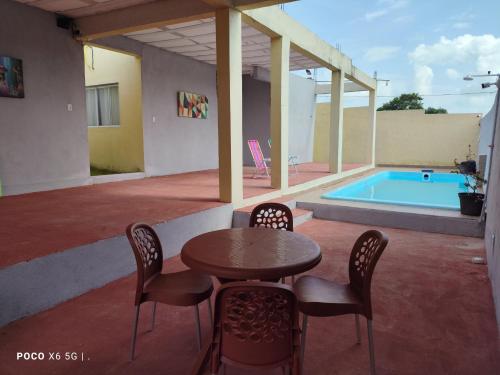 a patio with a table and chairs and a swimming pool at Casa Mineira - Flats novos em Ponta de Mangue - Maragogi in Maragogi