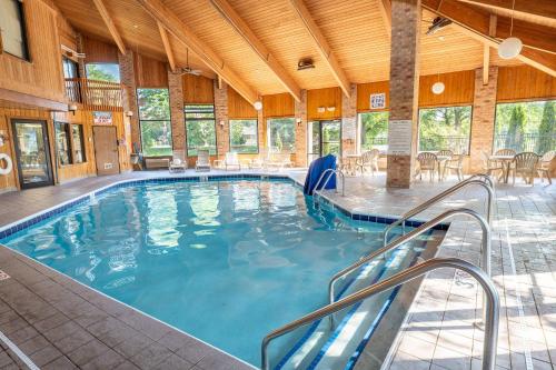 a large swimming pool in a building with tables and chairs at Quality Inn & Suites Sun Prairie Madison East in Sun Prairie