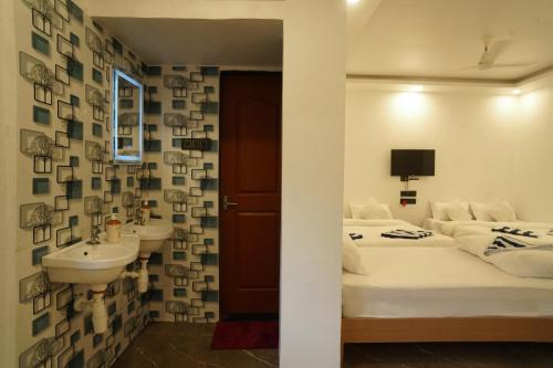 ein Schlafzimmer mit zwei Betten und einem Waschbecken in der Unterkunft Coral Sand Beach Resort By Privy Stays in Nagaon