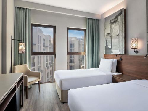 a hotel room with two beds and a desk at ibis Styles Dubai Gold District in Dubai
