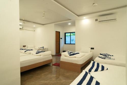 ein Zimmer mit drei Betten und einem Fenster in der Unterkunft Coral Sand Beach Resort By Privy Stays in Nagaon