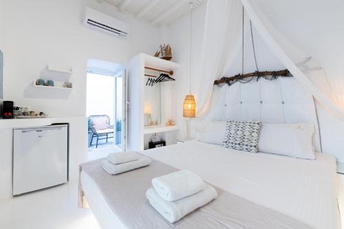 a white bedroom with a bed with two towels on it at Seablue Venice in Mýkonos City
