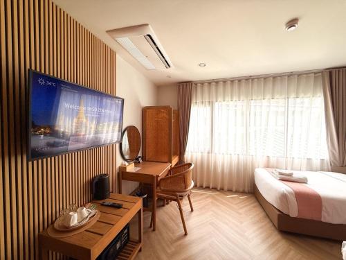 a hotel room with a bed and a desk and a television at SO Zen Hotel Silom Bangkok in Bang Rak