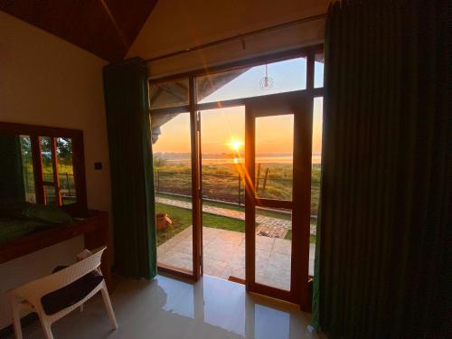 a room with a window looking out at the sunset at Sunrise Lake Resort in Polonnaruwa