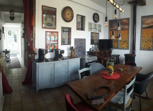 a kitchen with a table and a stove and a dining room at Maison Rose - Maison de village avec jardin privé, centre Capestang in Capestang