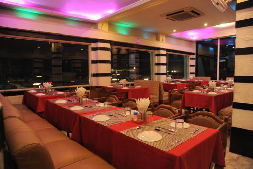 Un comedor con mesas y sillas rojas y ventanas. en Sonar Bangla's Motel Midway, en Howrah
