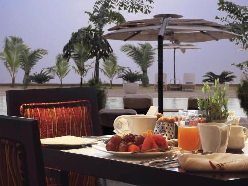 una mesa con una bandeja de fruta y una sombrilla en Novotel Mumbai Juhu Beach, en Bombay