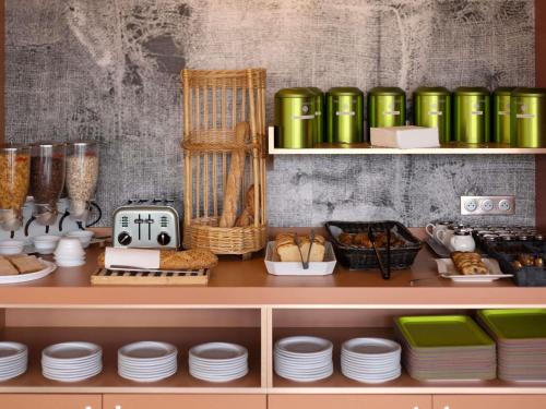 ein Regal mit grünen Gläsern und Tellern darauf in der Unterkunft ibis Styles Chinon in Chinon