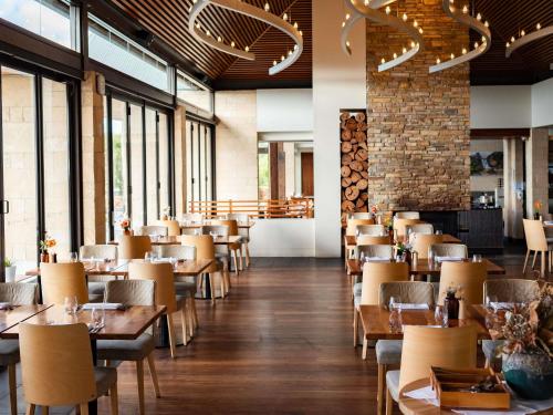 a restaurant with wooden tables and chairs and windows at Pullman Bunker Bay Resort Margaret River in Dunsborough