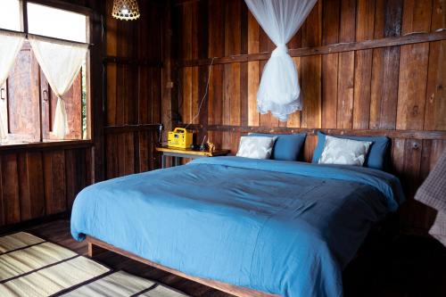 - une chambre avec un lit bleu dans un mur en bois dans l'établissement Hidden for Rest, à Ban Huai Khai