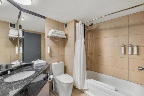 a bathroom with a toilet and a sink and a tub at Hotel Quartier, an Ascend Collection Hotel in Quebec City