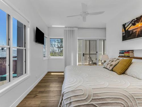 Un dormitorio blanco con una cama grande y ventanas en High Tide 4BR 3 level house Ocean views & Pool, en Kingscliff