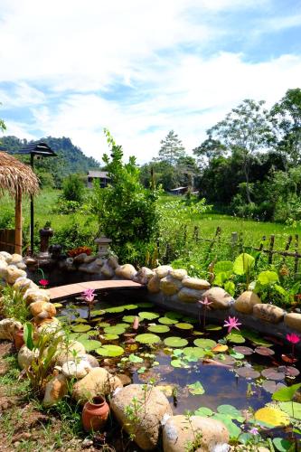 a pond with lilies and a bridge in a garden at The Bare Nest Retreat in Làng Lai