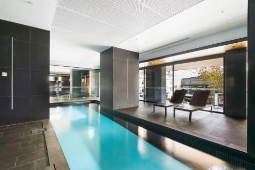 a swimming pool in a building with two chairs at Luxury living on top floors 3 Bedroom Mel CBD Pool in Melbourne