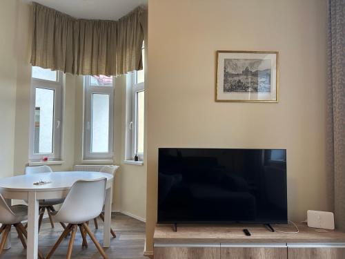 a living room with a large television and a table and chairs at Apartmán Marcello in Trenčianske Teplice