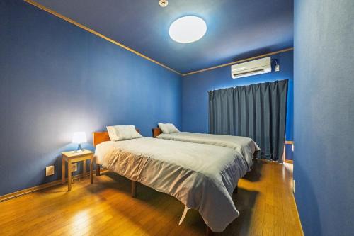 ein Schlafzimmer mit einem Bett und einer blauen Wand in der Unterkunft R-house 6th in Atami