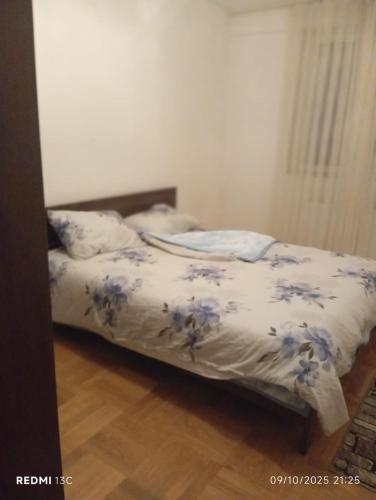 a bedroom with a bed with blue flowers on it at FushKosov in Kosovo Polje