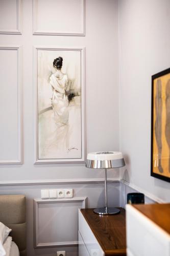 una habitación con una pintura de una mujer sentada en una silla en Maya's Flats & Resorts 44 - 3 Rooms Apartment On C, en Gdansk
