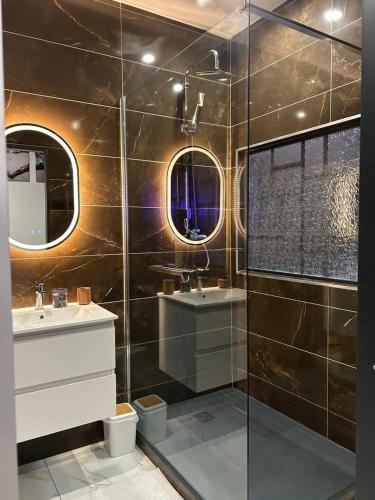 a bathroom with two sinks and a glass shower at Appartement Romantique Exceptionnel in Lorette