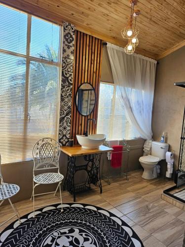a bathroom with a toilet and a table and chairs at Arrosa Guesthouse in Vrede