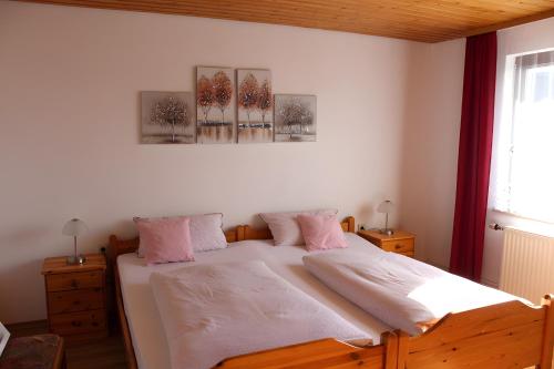 une chambre avec un lit avec des draps blancs et des oreillers roses dans l'établissement Ferienwohnung Haus Michel, 90 Qm, à Uhldingen-Mühlhofen