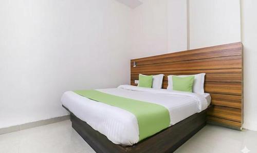 a bedroom with a large bed with a wooden headboard at FabHotel Red Ark Inn in Lāndrān