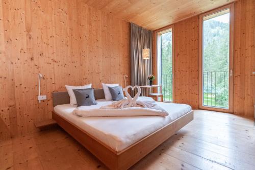 a bedroom with a large bed in a room with wooden walls at Alpenhotel Ammerwald in Reutte