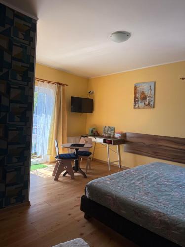 a bedroom with a bed and a table and a desk at Dom wczasowy Max in Darłowo