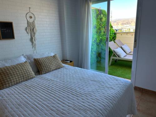 a bedroom with a white bed and a balcony at Ático junto al Teatro AUDITORIO de Roquetas de Mar in Roquetas de Mar
