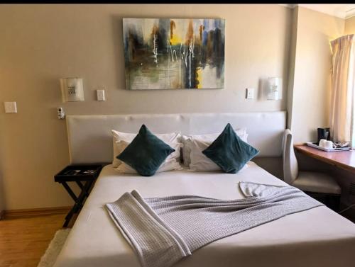 a bedroom with a white bed with blue pillows at Not Today Guest Lodge in Mthatha