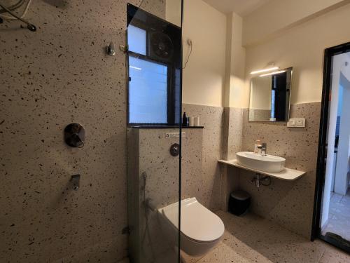 a bathroom with a shower and a toilet and a sink at Peaceful Candolim 2BHK Apartment - Family Stay, Scenic View, Pool in Candolim
