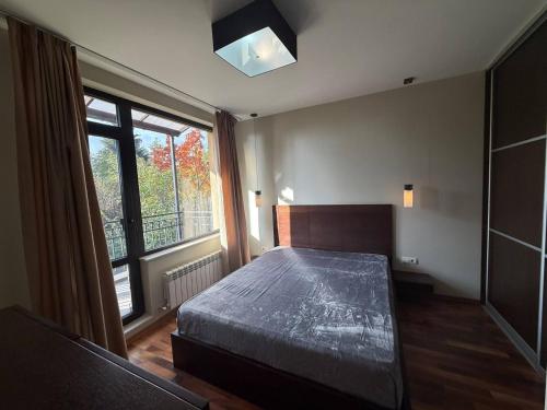 Un dormitorio con una cama y una ventana grande en Yarema Forest House, en Yarema residence zone