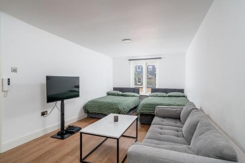 a living room with a couch and two beds at 16 Guests, 4 Studios, Groups, Contractors, Stockwell SW9 in London