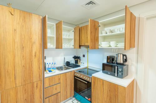 a small kitchen with wooden cabinets and a microwave at Elegant 1BR Escape - Chic Al Maryah Cozy Retreat in Abu Dhabi