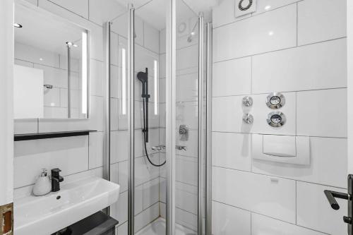 a white bathroom with a shower and a sink at Ferienwohnung im Zentrum von Oberstaufen in Oberstaufen