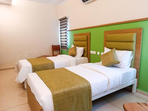 two beds in a room with green and white at tan90 Comfort Stays in Tiruchchirāppalli