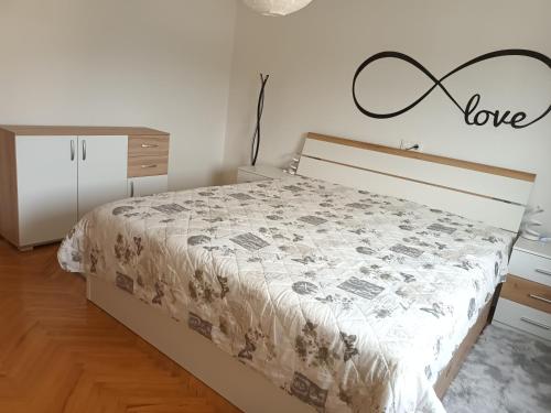a bedroom with a bed with a love sign on the wall at Apartment Carmen in Brezje