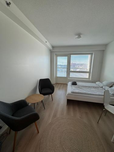 a bedroom with a bed and two chairs and a window at RD Apartments - Areenan Lumo in Tampere