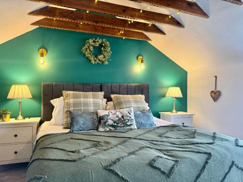 a bedroom with a green wall and a bed with pillows at Fallow Cottage, 3 Bedrooms, Woodburner - Heart of Stamford by Belmont Places in Lincolnshire