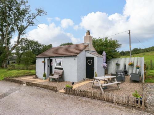 a small white cottage with a picnic table and a bench at High Wreah Bolt Hole in Whitehaven